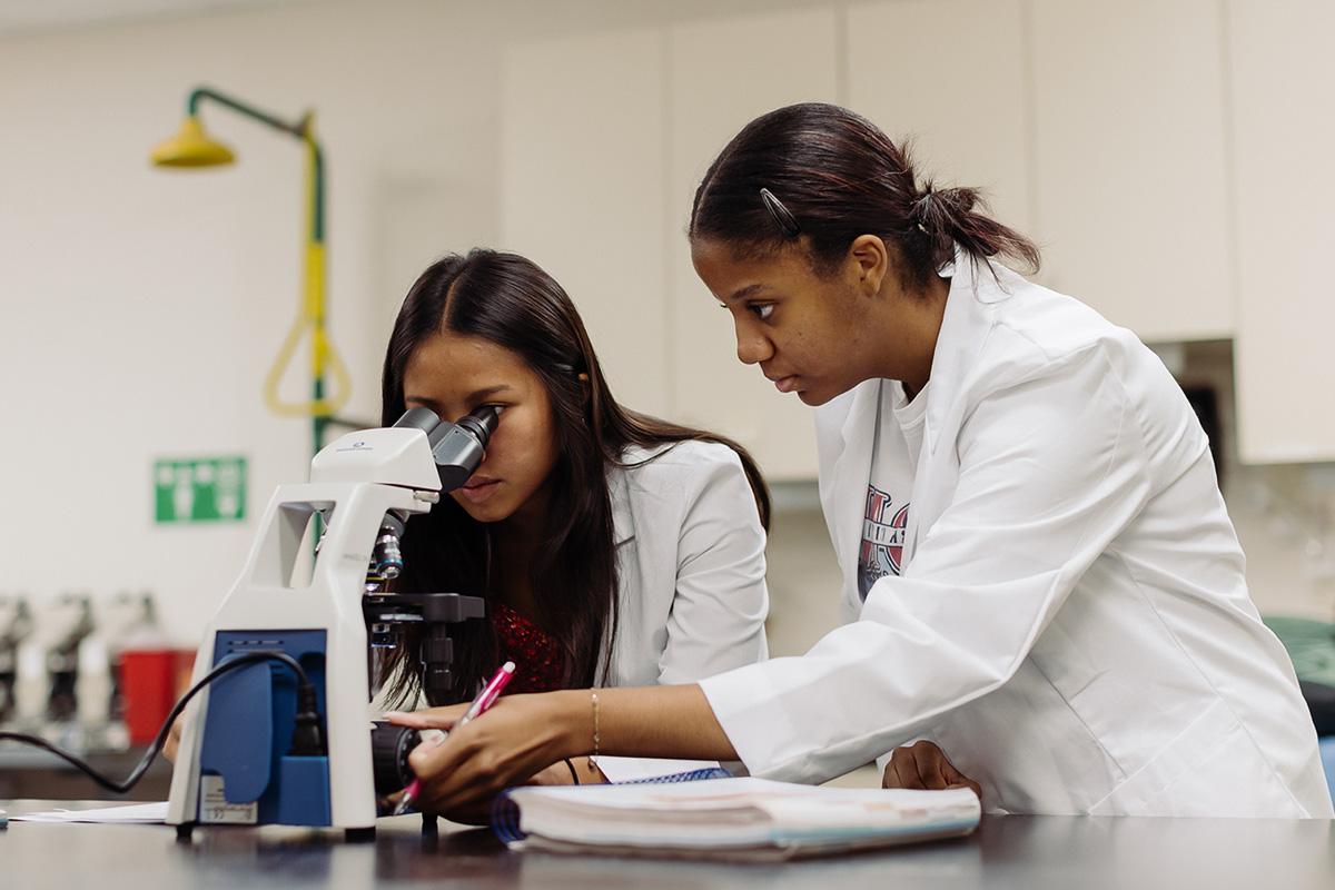 biology and health science students in a laboratory looking into a microscope